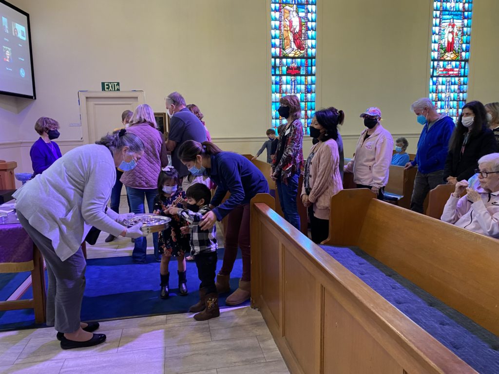 Parishioners sharing communion with COVID precautions